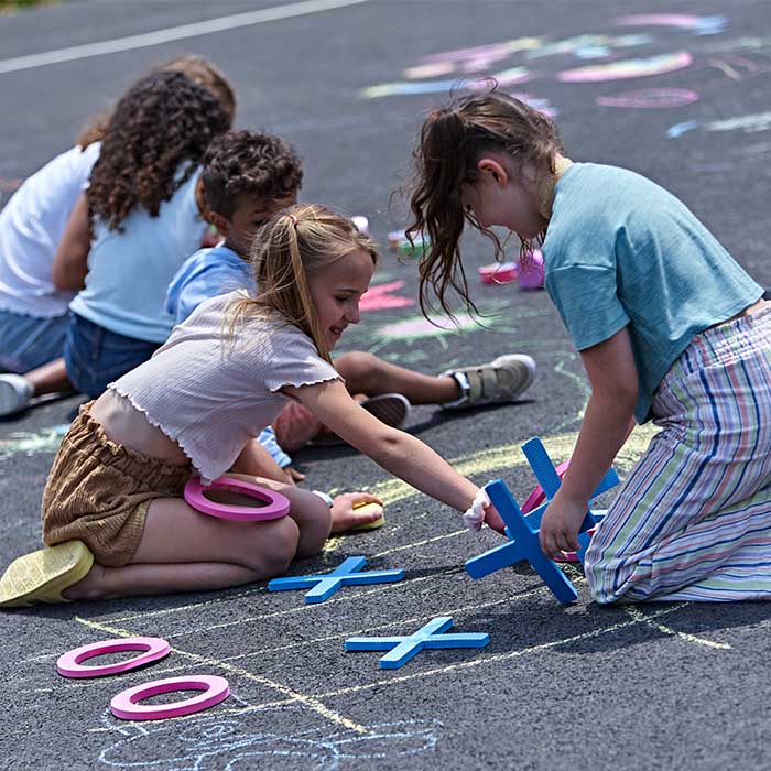 Children using sidewalk chalk on ground.